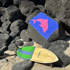 Colorful towel with a pink dolphin design on rocks and sand