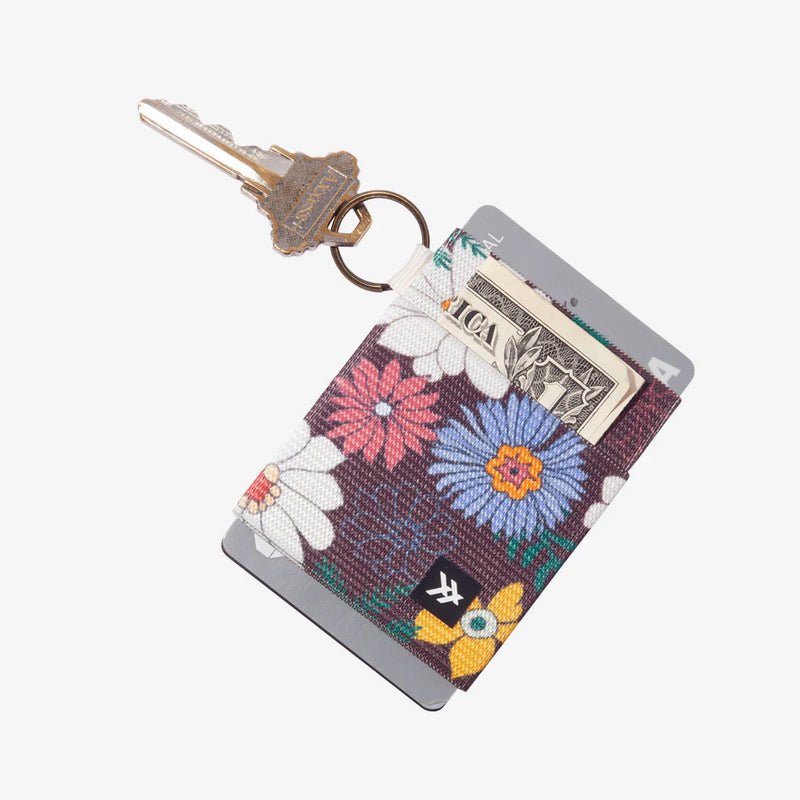 Floral patterned keychain card holder with keys and money on a white background