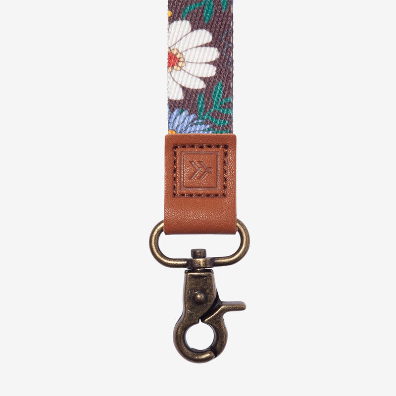 Floral patterned strap with brown leather buckle and metal clasp on a white background