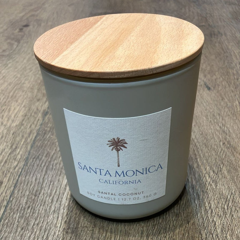 Candle with wooden lid labeled 'Santa Monica, California' on a wooden surface