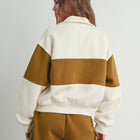 A woman shown from the back wearing a color-blocked sweatshirt and matching shorts in cream and mustard brown, photographed against a plain light gray studio background.
