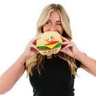 Person holding a plush toy shaped like a hamburger with a smiling face.