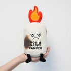 Plush toy resembling a campfire with a flame on top, displaying 'Not a Happy Camper' text, held by a hand against a light gray background.