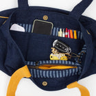 Navy blue backpack with yellow handles containing a phone, wallet, and keys on a white background