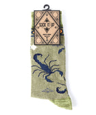 A single sock hanging from a black hanger with a paper tag that reads 'SOCK IT UP MEN'S CROW'. The sock is light olive green with a large navy blue scorpion graphic and a matching green knit toe and heel.