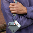 Person holding a keychain with a phone case and cards against a blurred background