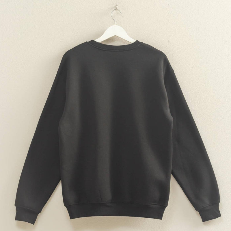 Black sweatshirt on a hanger against a beige wall