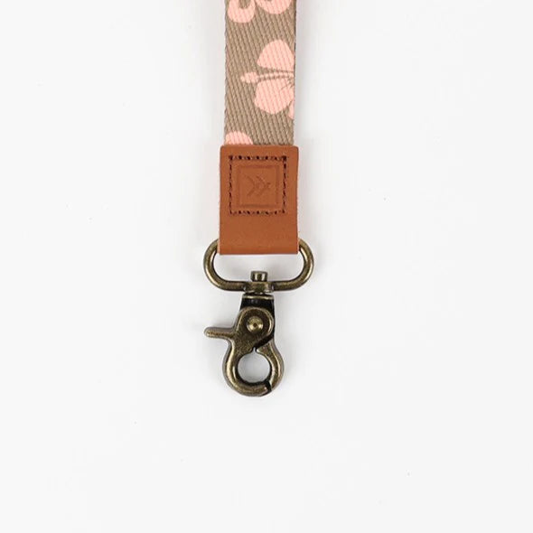 Floral patterned strap with a brown leather patch and metal clasp on a white background