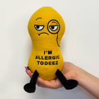 Yellow plush toy with a face and text 'I'm Allergic Todeez' held in a hand against a white background
