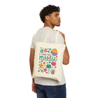 A man wearing a white t-shirt and blue jeans is shown from the back, carrying a cream-colored canvas tote bag over his shoulder. The bag features a colorful graphic with the text 'I LOVE YOU MALIBU' surrounded by tropical illustrations like palm trees, a sun, and flowers.