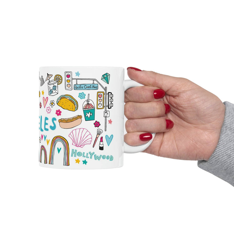 Hand holding a mug with colorful illustrations and text on a white background