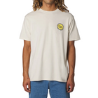 A man wearing a cream-colored short-sleeve t-shirt with a yellow and black circular graphic on the left chest, paired with blue jeans, against a light gray background.