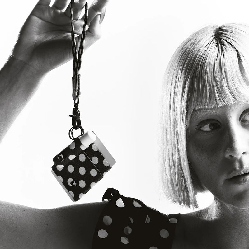 Black and white polka dot keychain held by a person with a woman wearing a matching outfit.
