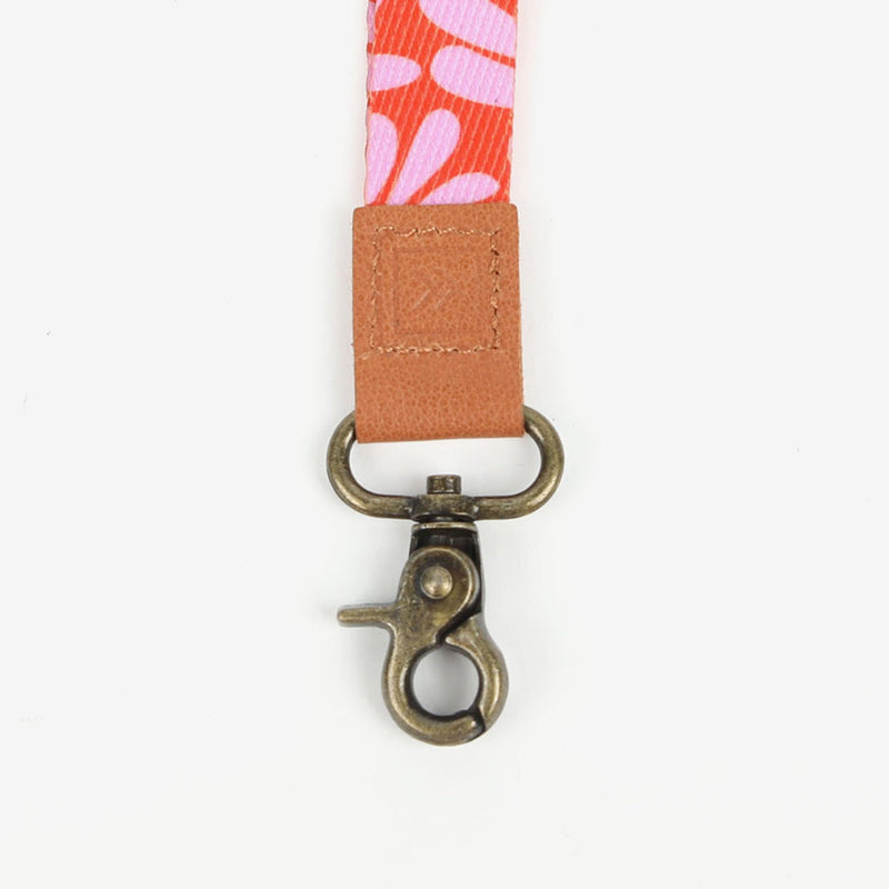 Floral lanyard with a brown leather patch and metal clasp on a white background