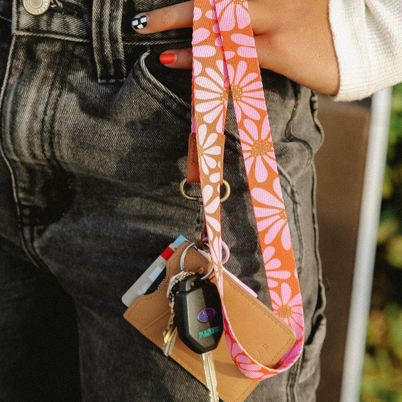 Person holding a floral lanyard over a keychain and card holder 