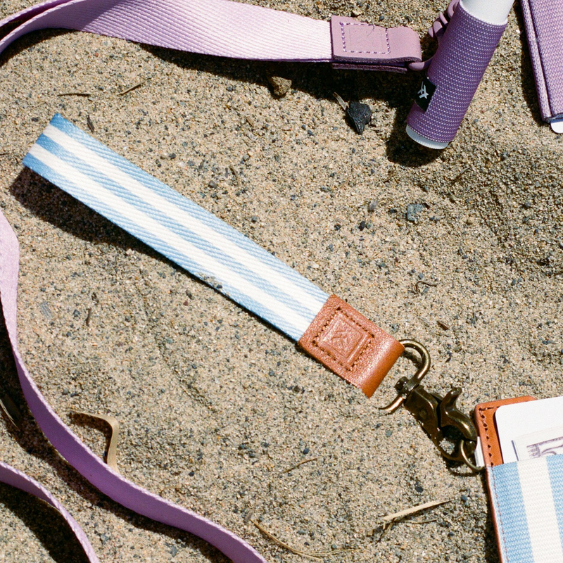 Strap with a brown buckle and gold clasp on a sandy surface